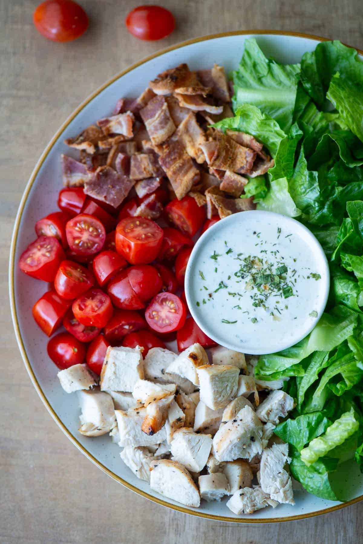 Overhead view of a partial plate of Chicken BLT Salad with ranch dressing in the middle