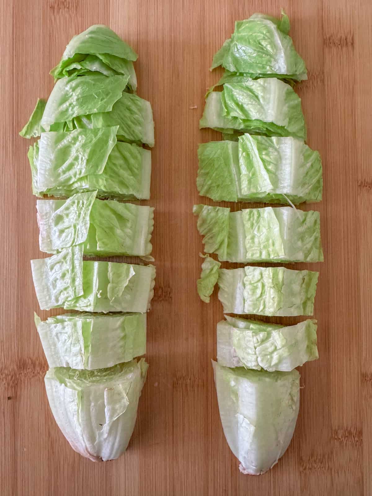 Overhead photo of cut romaine lettuce on a cutting board.