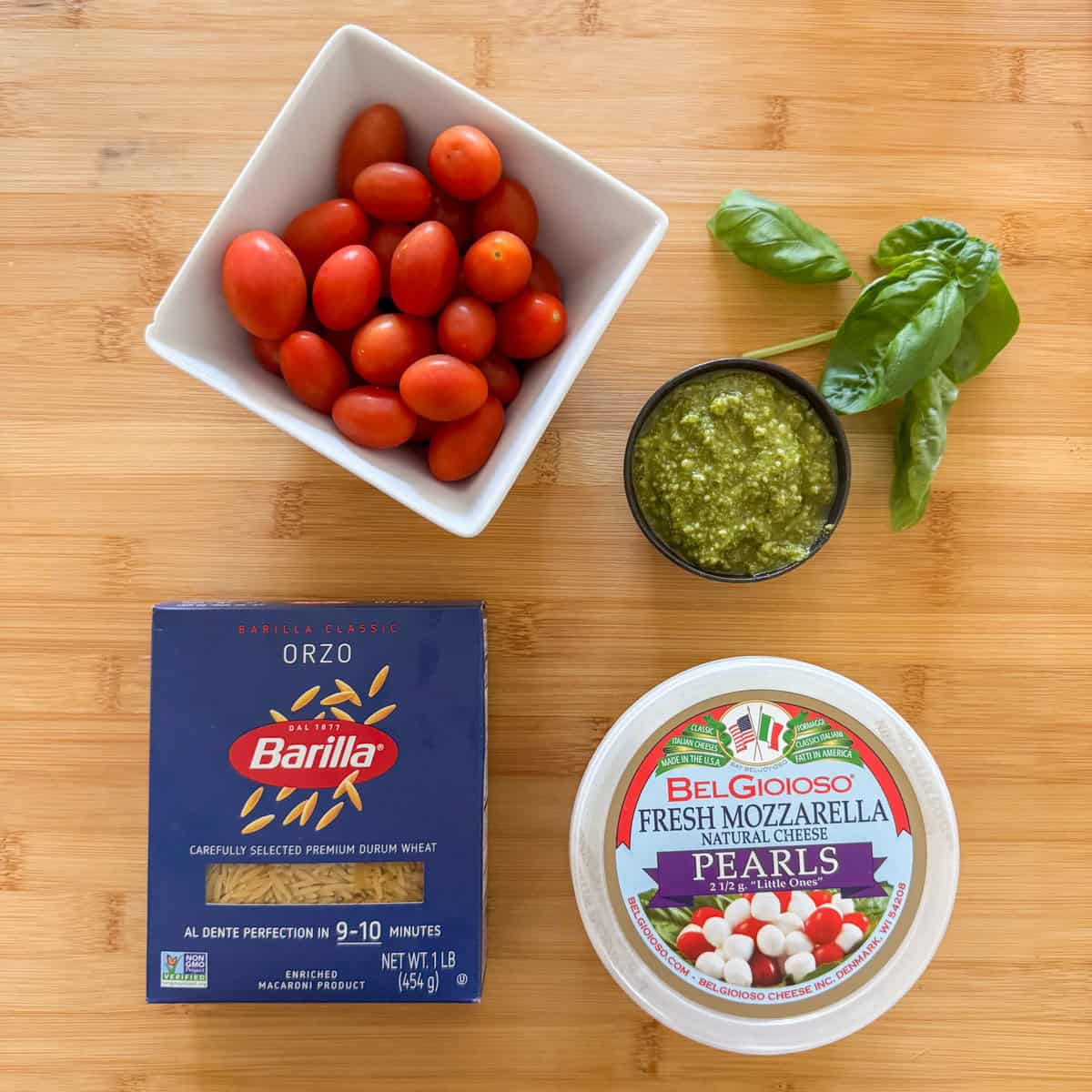 Ingredients needed for pesto orzo pasta salad: orzo pasta, grape tomatoes, mozzarella cheese and basil pesto.