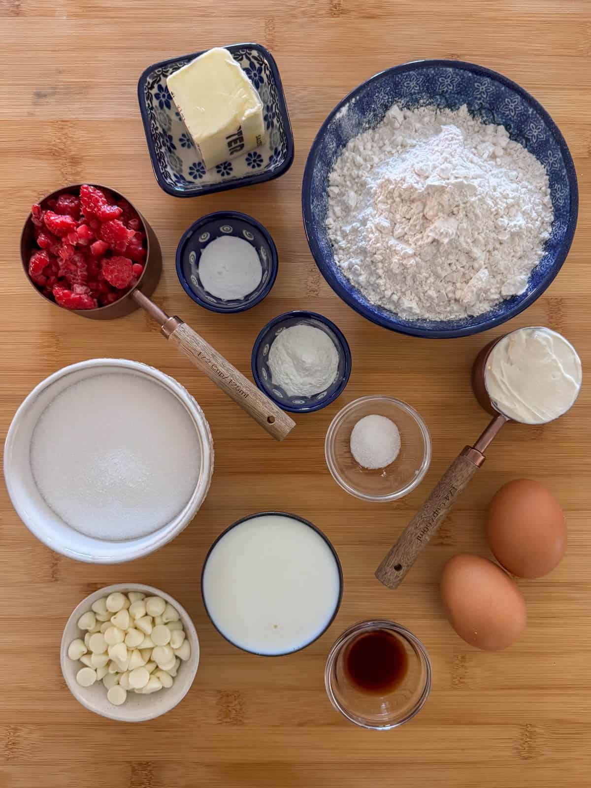 Ingredients needed for raspberry white chocolate cupcakes: cake flour, baking powder, baking soda, salt, salted butter, white sugar, eggs, milk, sour cream, vanilla, frozen raspberries and white chocolate