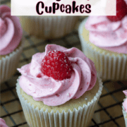 Overhead photo of raspberry white chocolate cupcakes where one is centered and surrounded by others in partial view with a text overlay that says Raspberry White Chocolate Cupcakes
