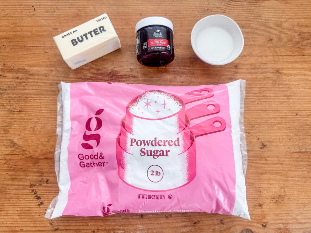 Ingredients needed to make vanilla bean buttercream frosting: powdered sugar, salted butter, vanilla bean paste and whole milk (or heavy cream).