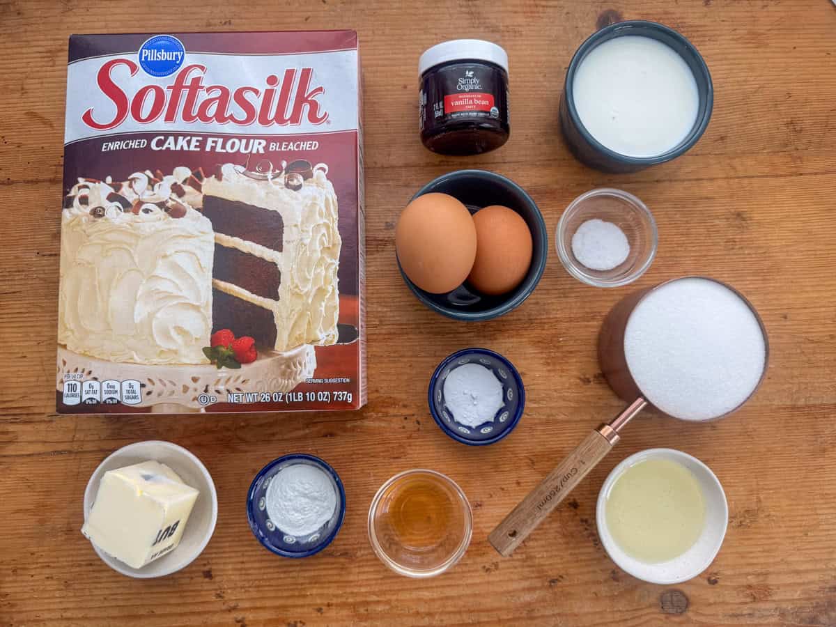 Ingredients needed to make vanilla bean cupcakes: cake flour, vanilla bean paste, whole milk, eggs, salt, baking soda, white sugar, slated butter, baking powder, vinegar and neutral oil