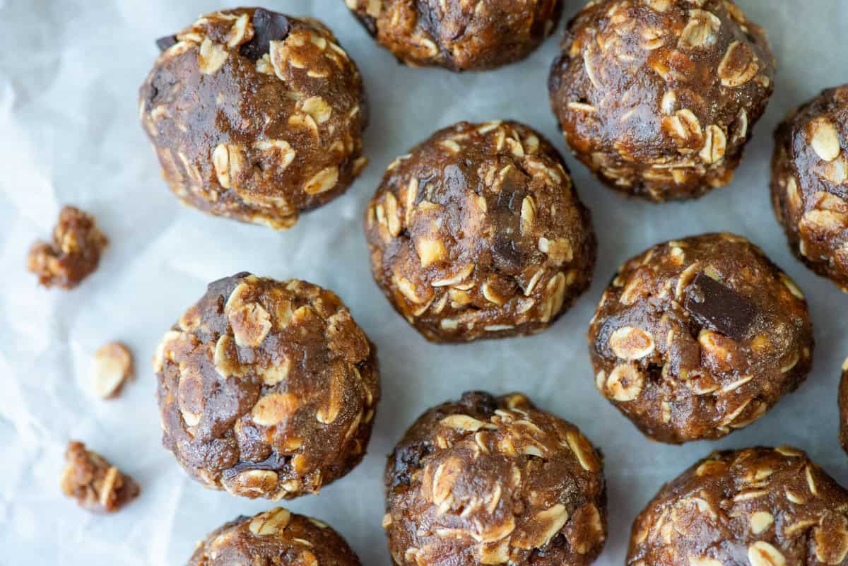 Overhead view of chocolate protein powder balls on a cookie sheet with crumbs to the left side