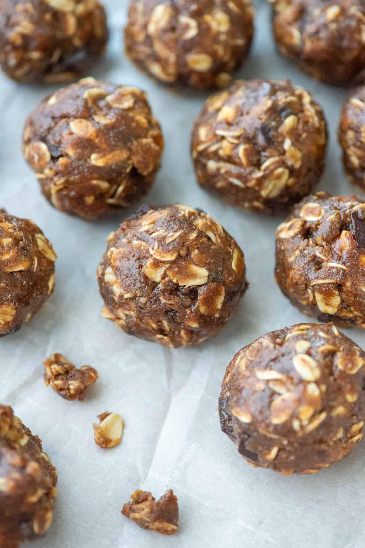 Overhead view of chocolate protein powder balls on a cookie sheet with some crumbs to the front