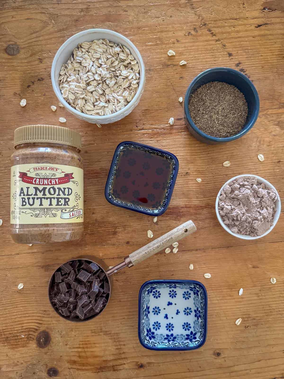 Ingredients needed to make chocolate protein powder bites: chocolate protein powder, water, crunchy almond butter, old fashioned oats, ground flaxseed, maple syrup and chocolate chips