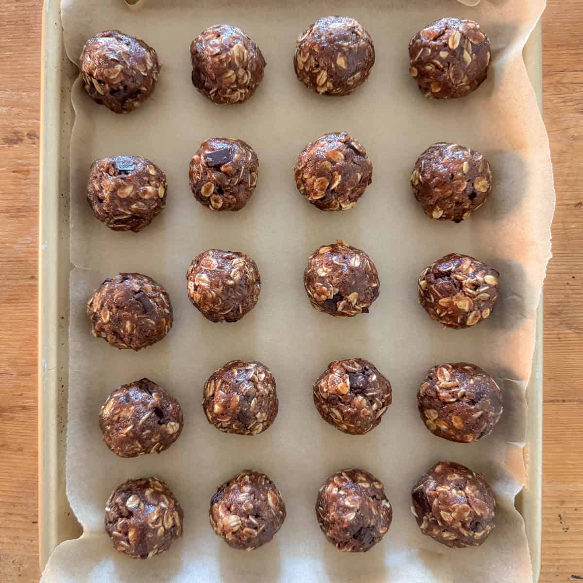 Last step of making chocolate protein powder balls: shape into balls using 2 tablespoons of the mixture and place on a baking sheet lined with parchment paper and then refrigerate to set