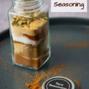 Side view of a jar of homemade taco seasoning while the spices are still layered in the jar before they have mixed together with the top of the jar that says Taco Seasoning in front with a title overlay that says Homemade Taco Seasoning