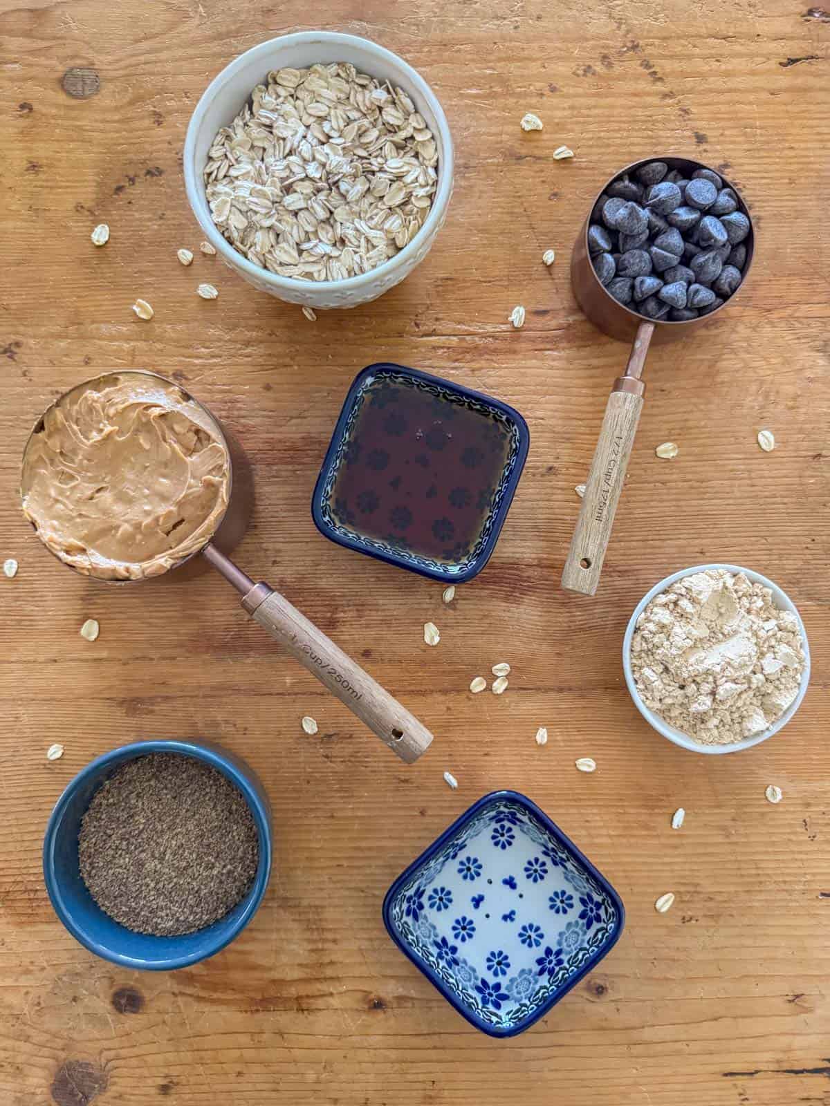 Ingredients to make no bake oatmeal peanut butter balls: peanut butter powder, water, crunchy peanut butter, old fashioned oats, ground flaxseed, maple syrup and chocolate chunks.