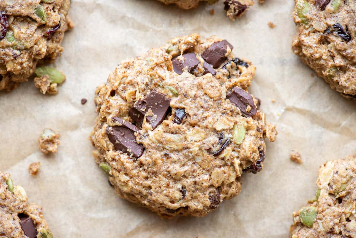 Overhead view of an oatmeal breakfast cookie on parchment paper with more oatmeal breakfast cookies in partial view