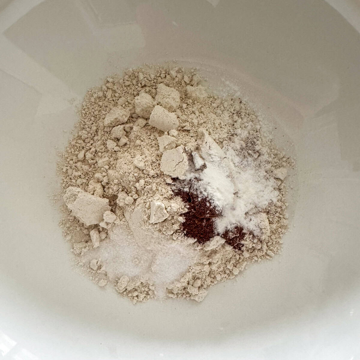 Overhead view of oat flour, baking powder, cinnamon and salt in a medium bowl