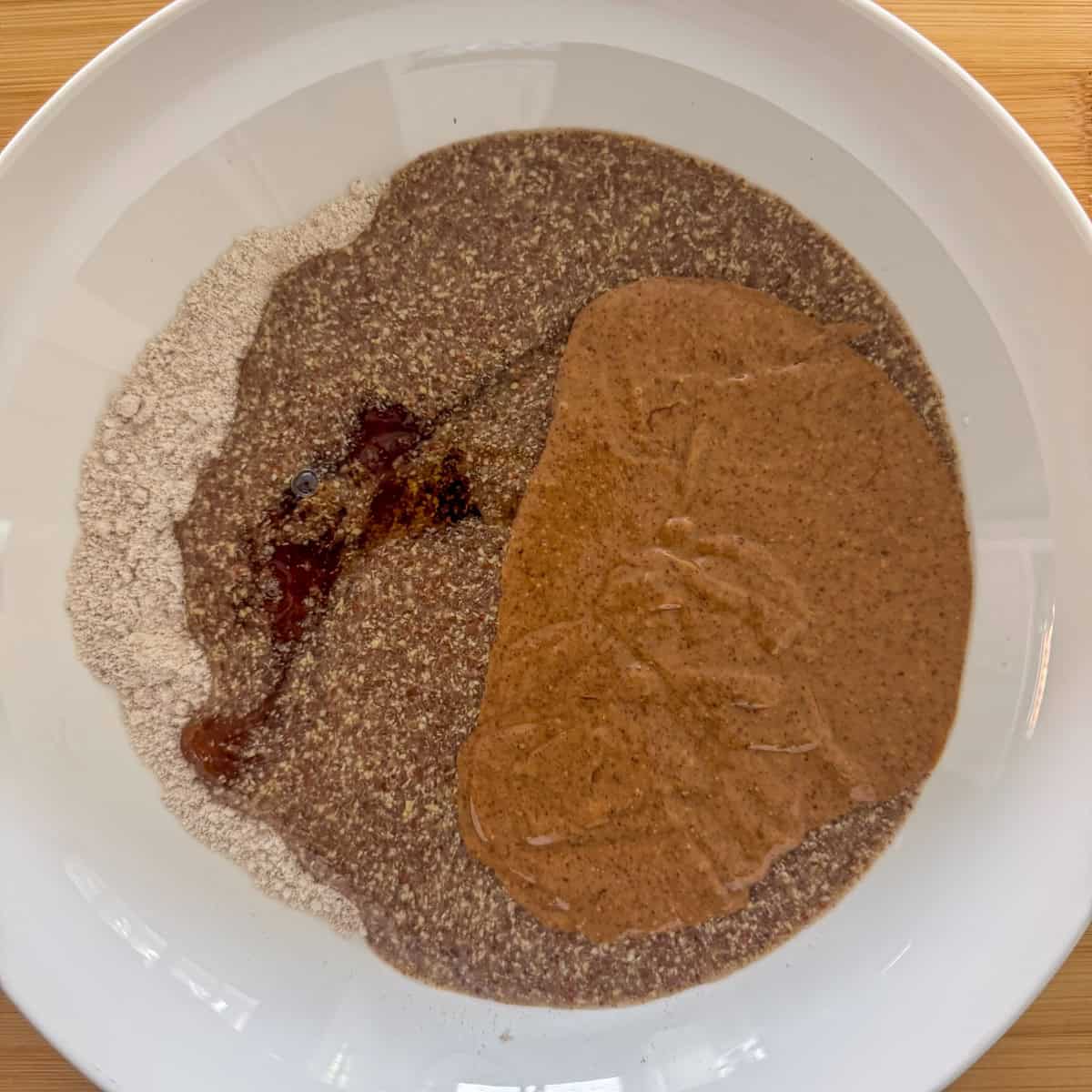 Almond butter, flaxseed meal with water mixture and maple syrup added to the medium bowl over the dry ingredients