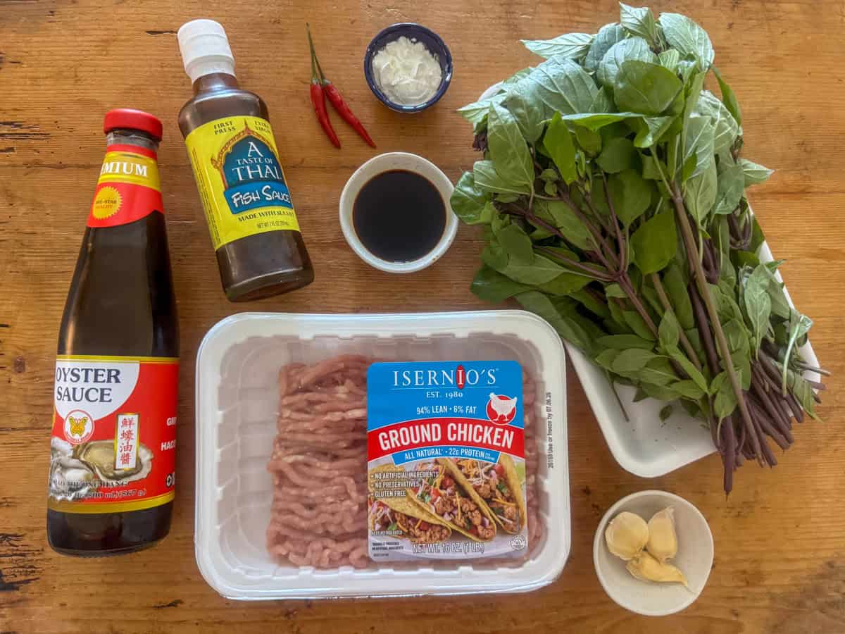 Ingredients needed to make Thai basil chicken: ground chicken, cornstarch, oyster sauce, fish sauce, soy sauce, garlic, Thai red chilies and Thai basil.