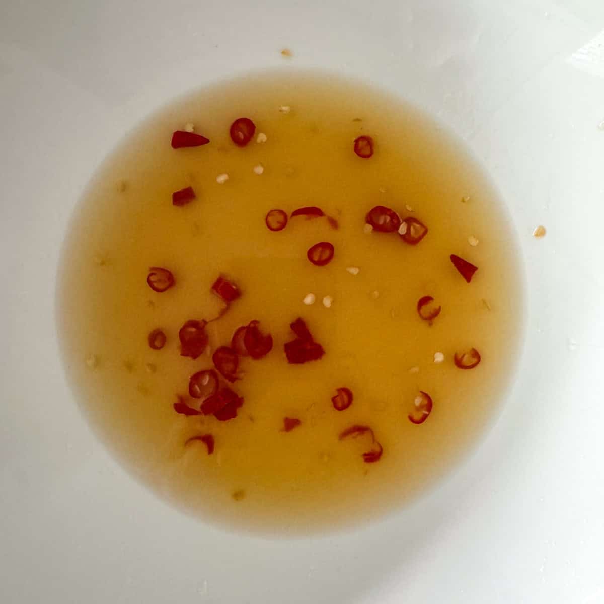 The Thai beef salad dressing in a medium bowl: fish sauce, lime juice, Thai red chili peppers and sugar