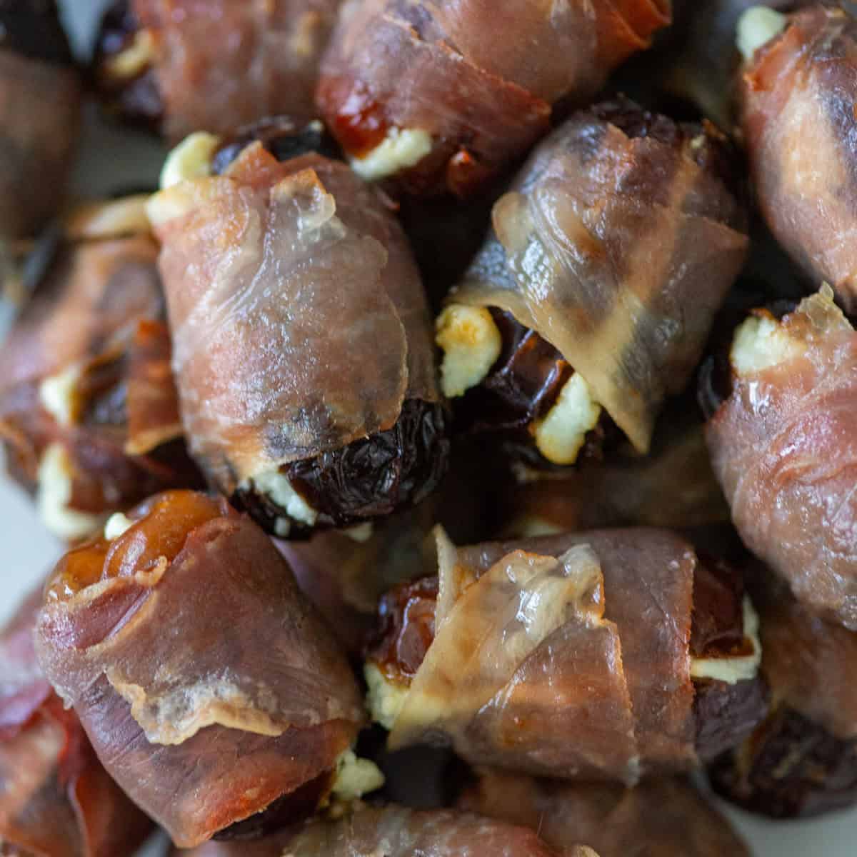Overhead view of a pile of cooked prosciutto wrapped dates.
