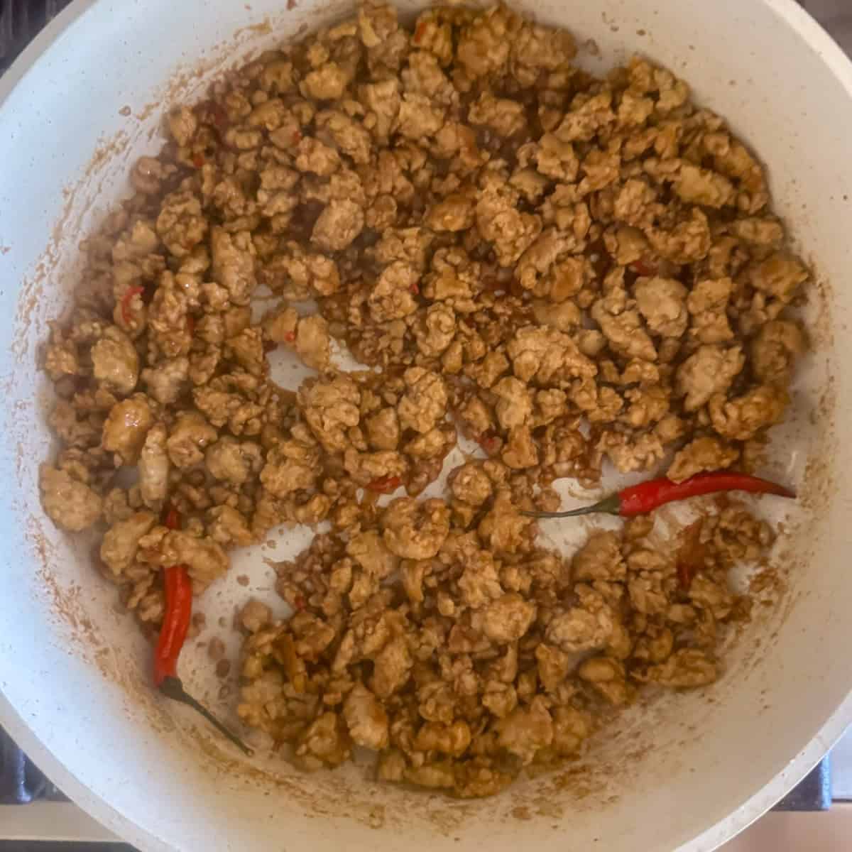 Ground chicken in a skillet after the stir fry sauce has been mixed in