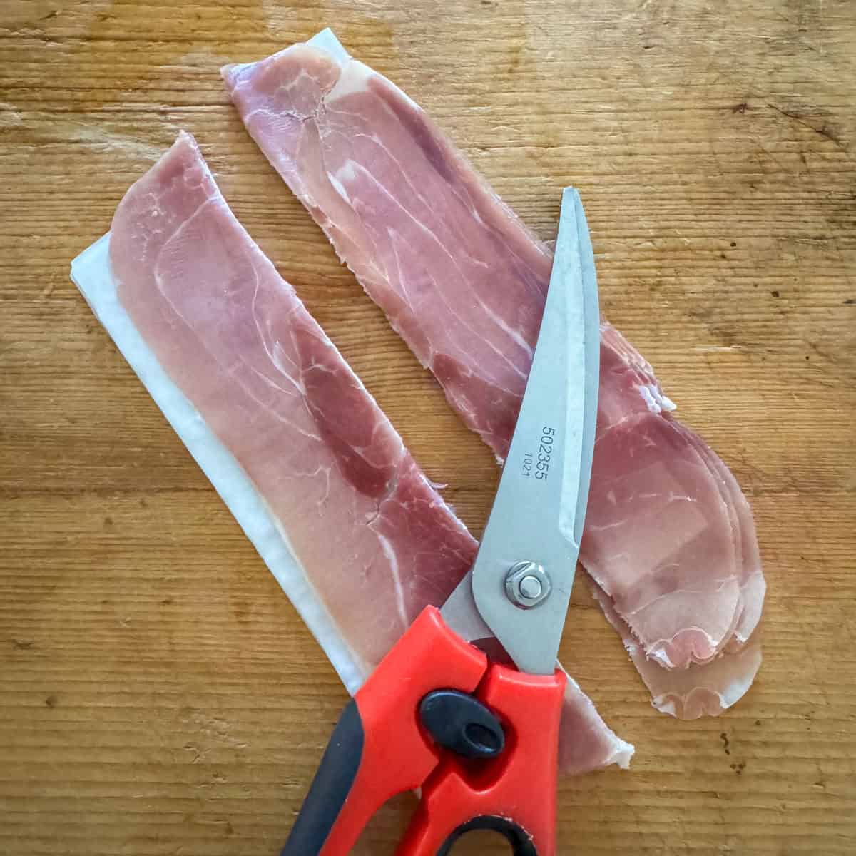 Step 1 in making prosciutto wrapped melon: cut the prosciutto in half lengthwise