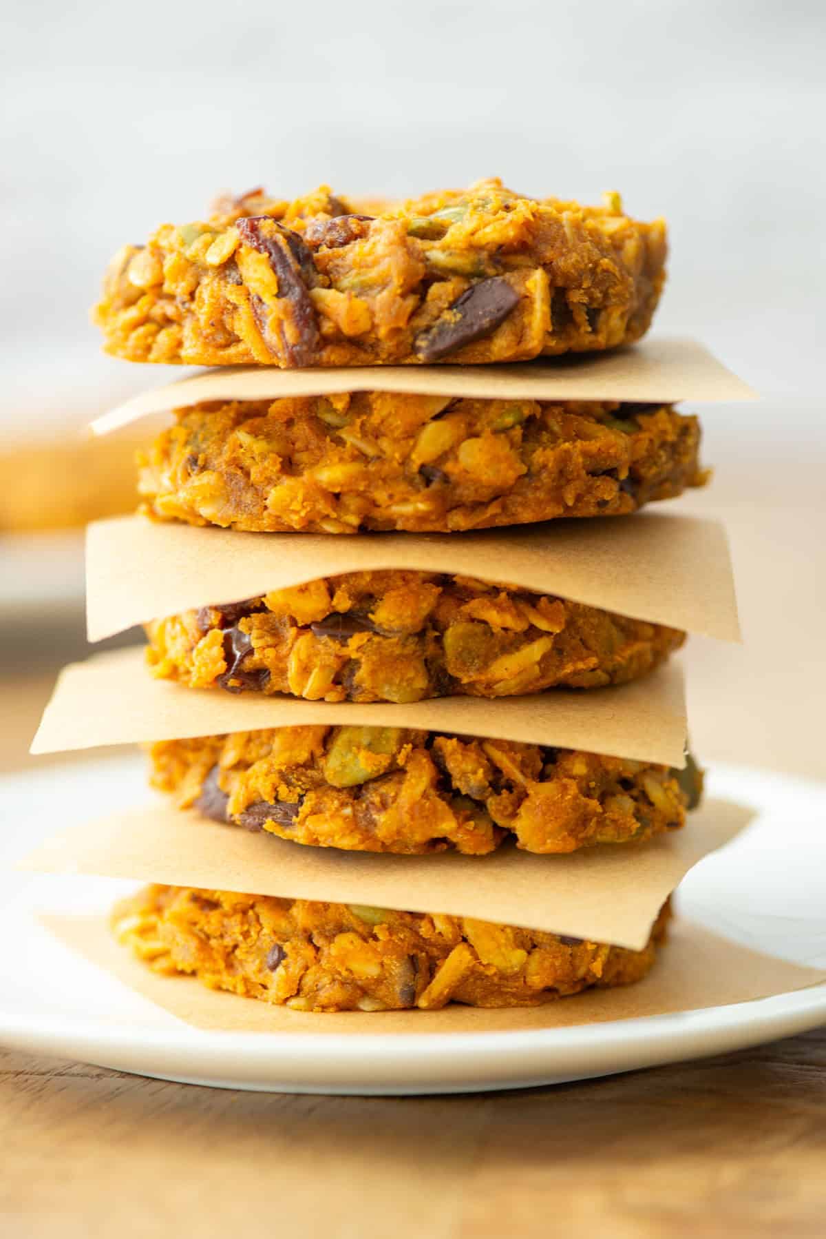 Side view of 5 vertically stacked pumpkin breakfast cookies with a piece of parchment paper in between each cookie