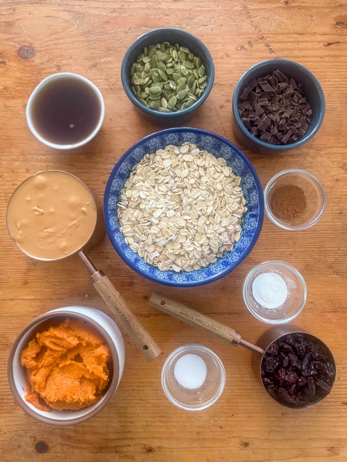 Ingredients needed for pumpkin breakfast cookies: pumpkin puree, pumpkin pie spice, baking powder, salt, almond butter, maple syrup, oatmeal, dried cherries and green pumpkin seeds