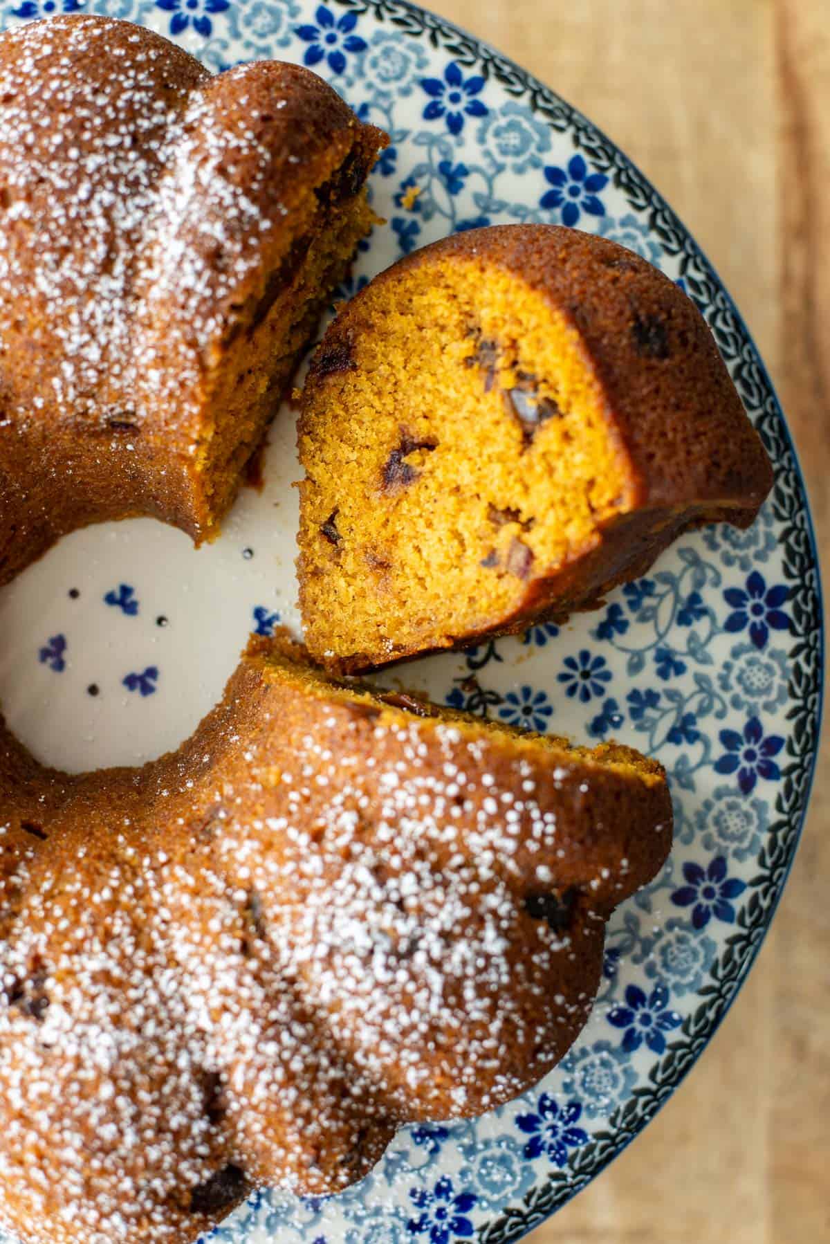 Overhead photo of the right half of pumpkin date bread made in a bundt pan with one slice cut out and flipped on its side so that you can see the inside of the bread