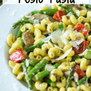 Overhead angled view of a plate of vegetable pesto pasta made with asparagus, red bell peppers and mushrooms and garnished with extra parmesan cheese with a title overlay that says Vegetable Pesto Pasta
