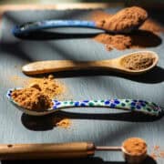 Angled side view of 4 varying types of teaspoons all with different spices on them in high contrast light. There's a title overlay at the top that says Apple Pie Spice Blend