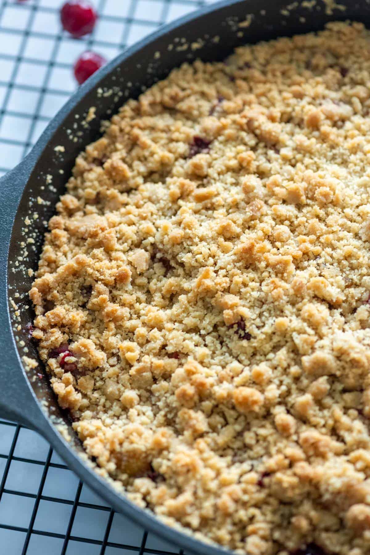Overhead photo of a half of a just baked cranberry apple crumble that's sitting on a cooling rack