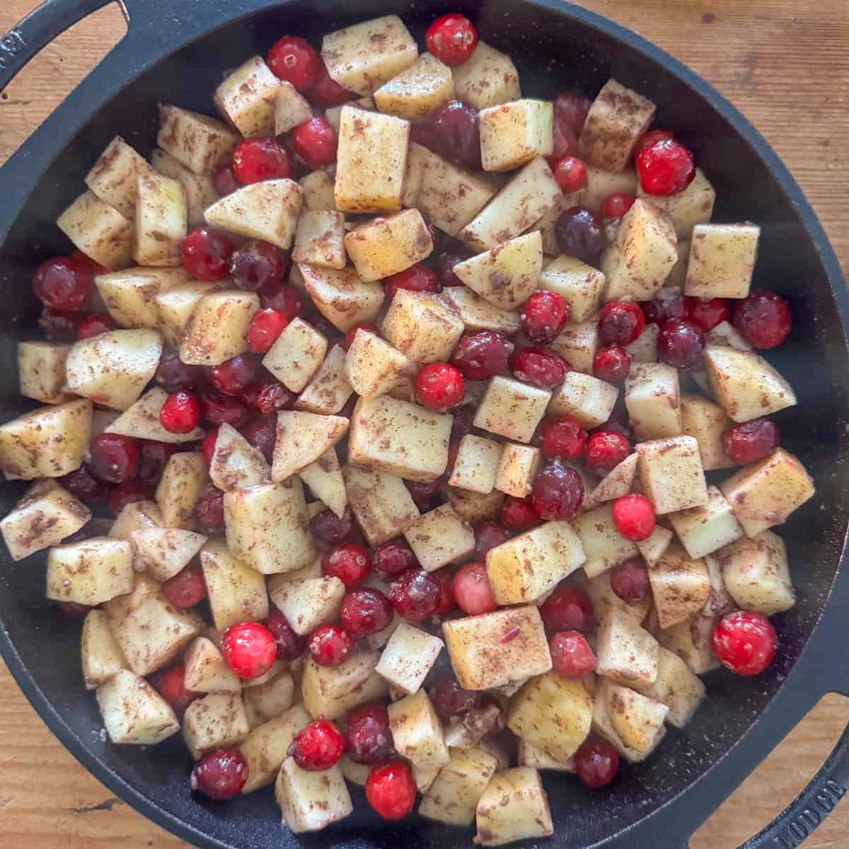 Step 2 of making cranberry apple crumble: put the tossed apples and cranberries in a 10 inch round pan or 9 inch square pan