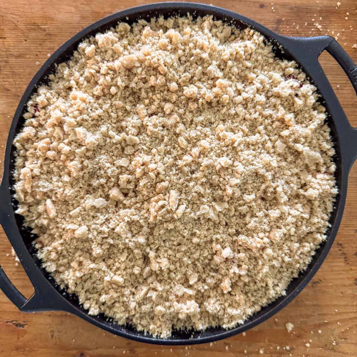 Step 4 of making a cranberry apple crumble: add the crumble topping over the apple and cranberries