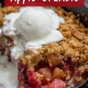 Overhead angled photo of the last couple servings of cranberry apple crumble in a cast iron pan with a scoop of vanilla bean ice cream melting on top with a title overlay that says Easy Cranberry Apple Crumble