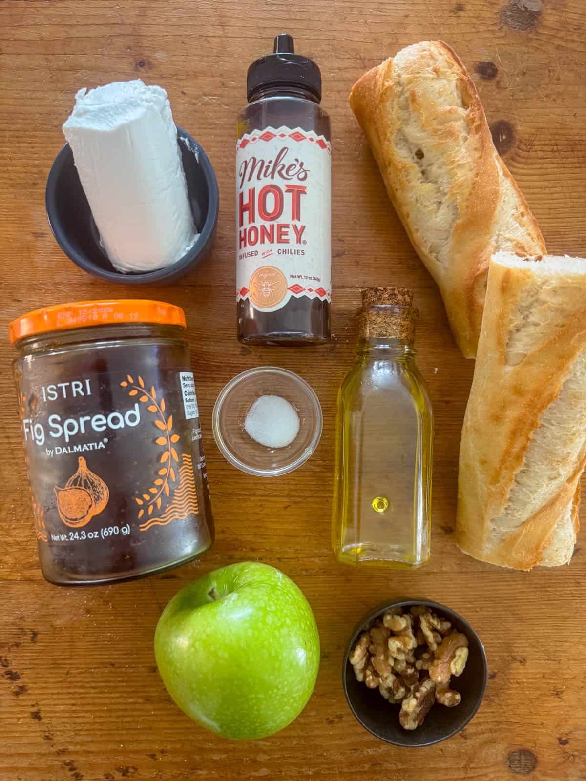 Ingredients needed to make apple, goat cheese and fig jam crostini: baguette, olive oil, goat cheese, salt, fig jam, Granny Smith apple hot honey and walnuts