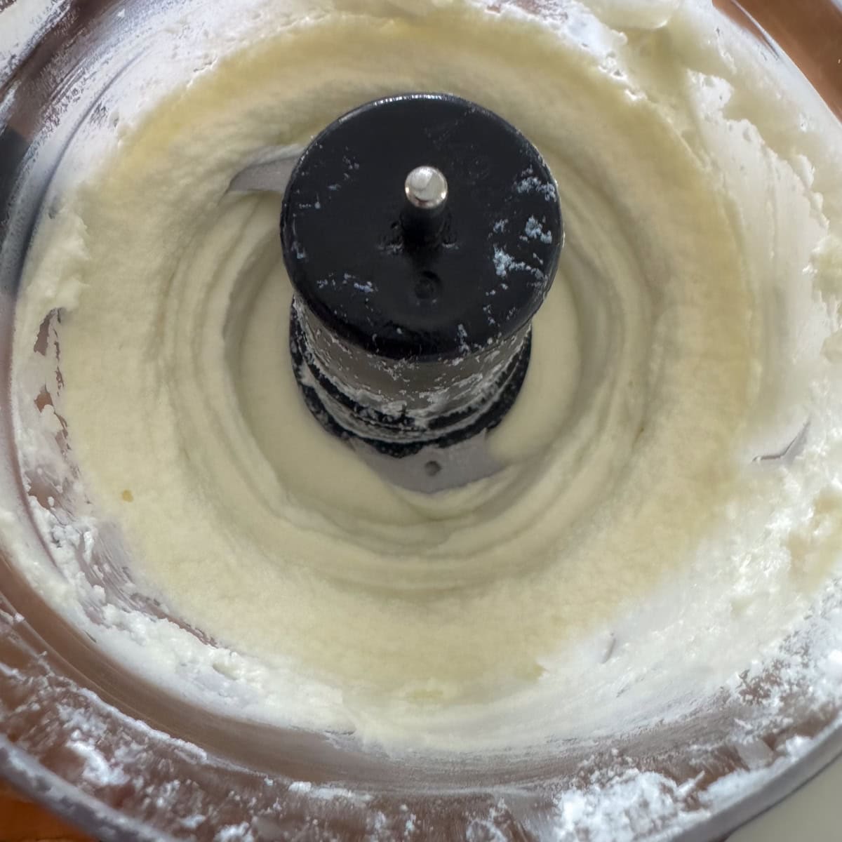 Goat cheese being whipped in a mini food processor.
