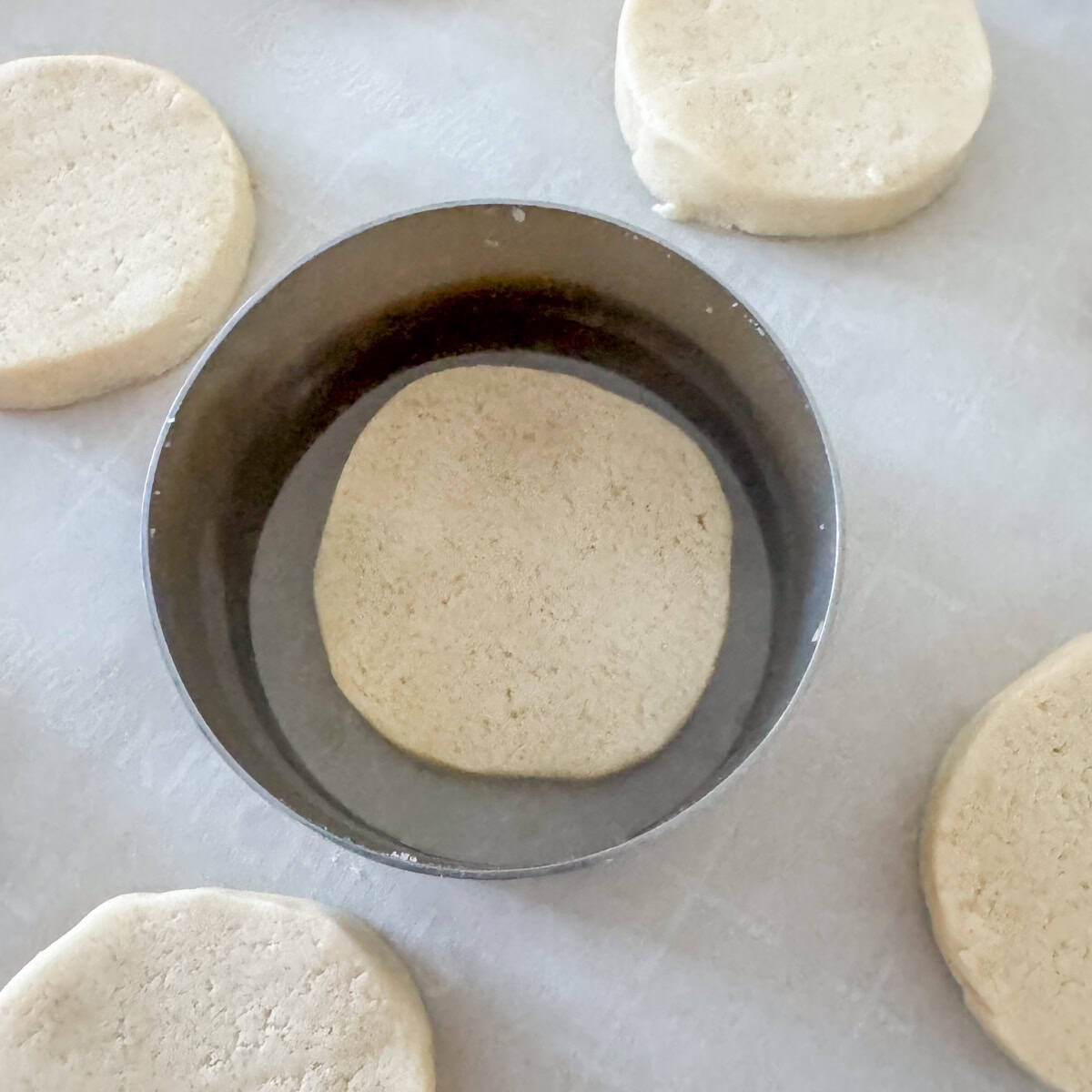 Overhead view of a ring around an unbaked cookie. If you swirl the ring around the unbaked cookie lightly touching the edges, it makes the unbaked cookie more round