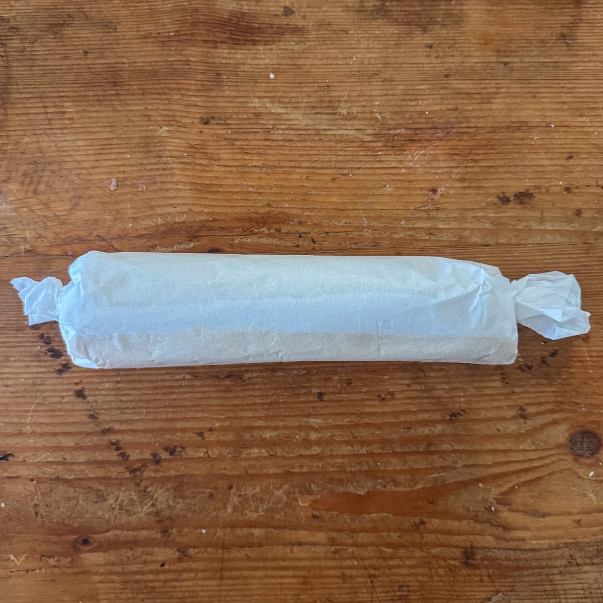 Dairy free shortbread cookies rolled into a log and wrapped in parchment paper