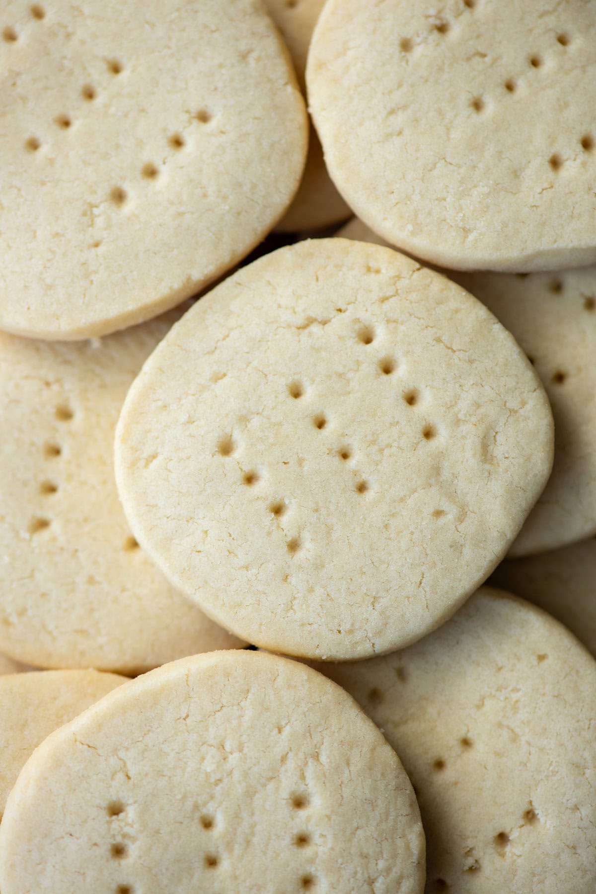 Overhead view of undecorated dairy free shortbread cookies stacked on more cookies on a cookie sheet