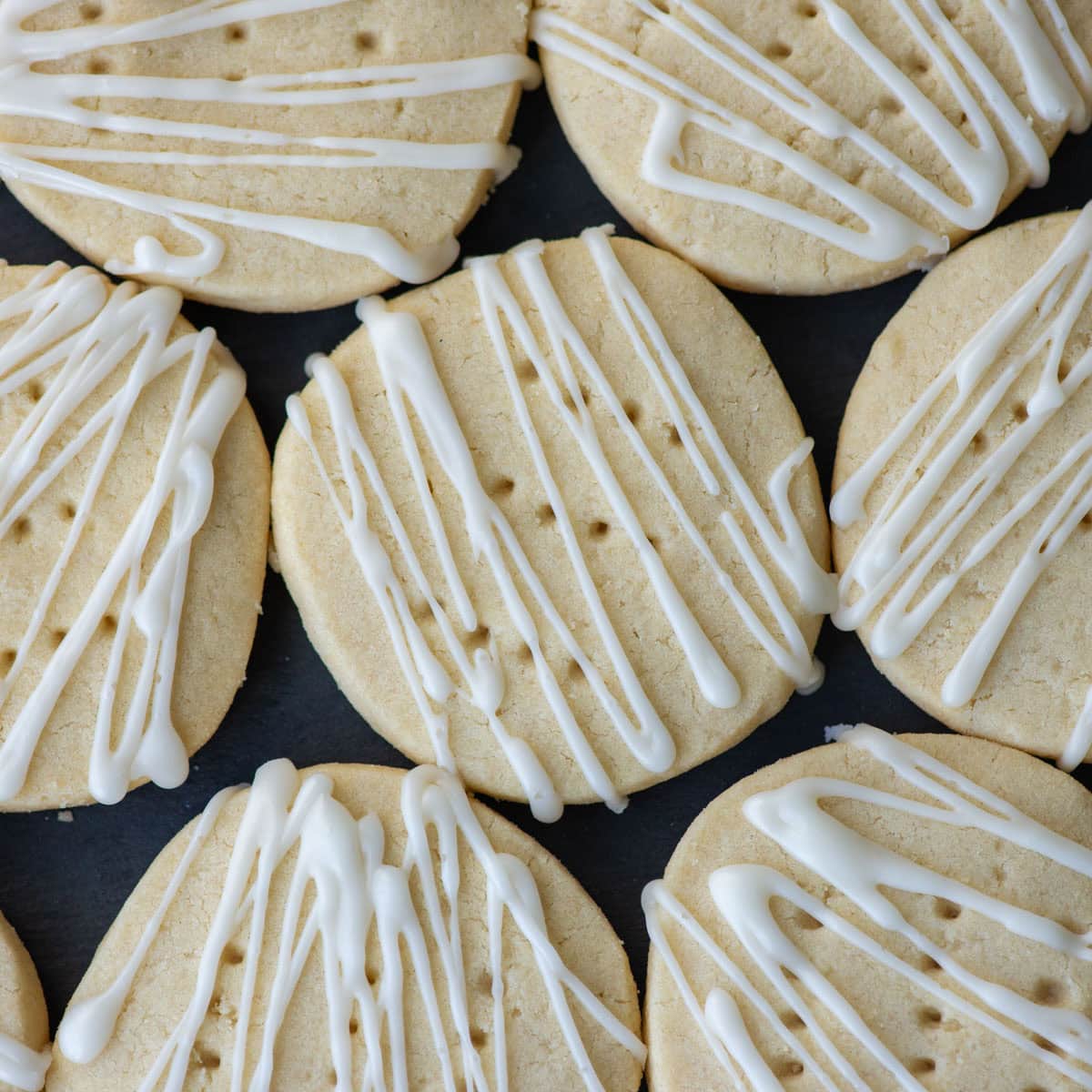Overhead photo of dairy free shortbread cookies decorated with a frosting glaze on a platter.