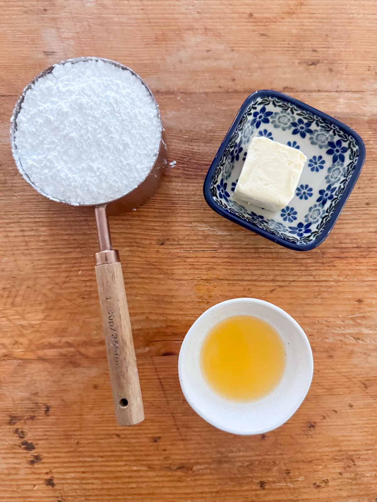 Overhead view of ingredients needed for optional glaze: powdered sugar, dairy free butter and fruit juice such as lemon or orange