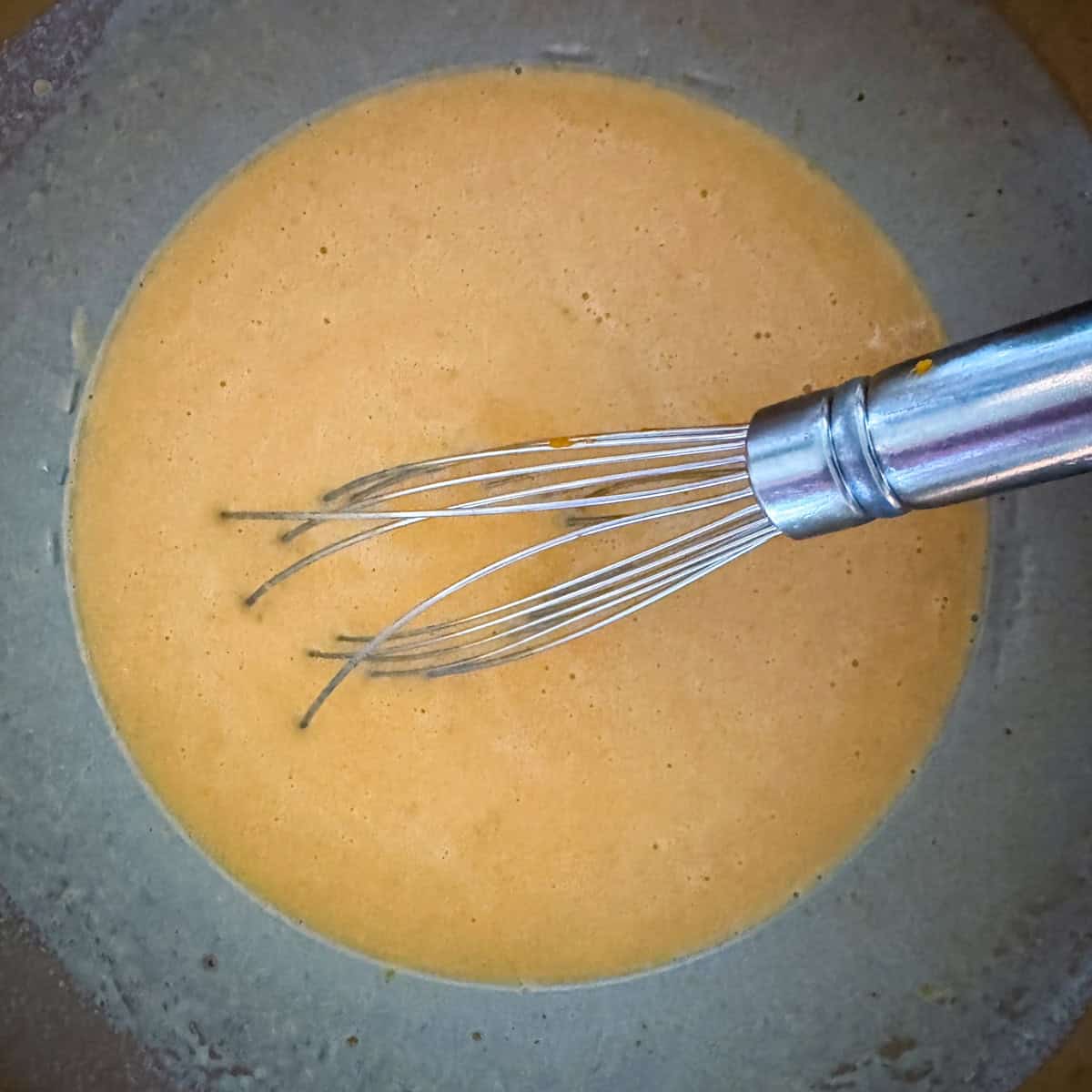 Second step in making pumpkin spice waffles: beat eggs in a medium bowl and then stir in the canned pumpkin, warm milk, melted butter and vanilla until combined.