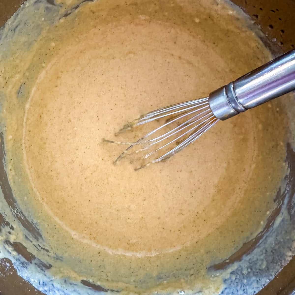 Third step in making pumpkin spice waffles: pour the wet ingredients into the dry ingredients and stir just until combined and no large lumps remain, about 30 seconds. Avoid over-mixing.
