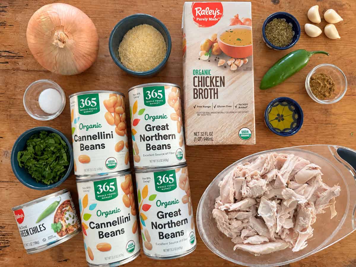 Ingredients needed for turkey and white bean chili recipe: cooked turkey, great northern beans, cannellini beans, green chilies, yellow onion, jalapeno, chicken broth, corn meal, cilantro, cumin, olive oil, garlic, oregano and salt.