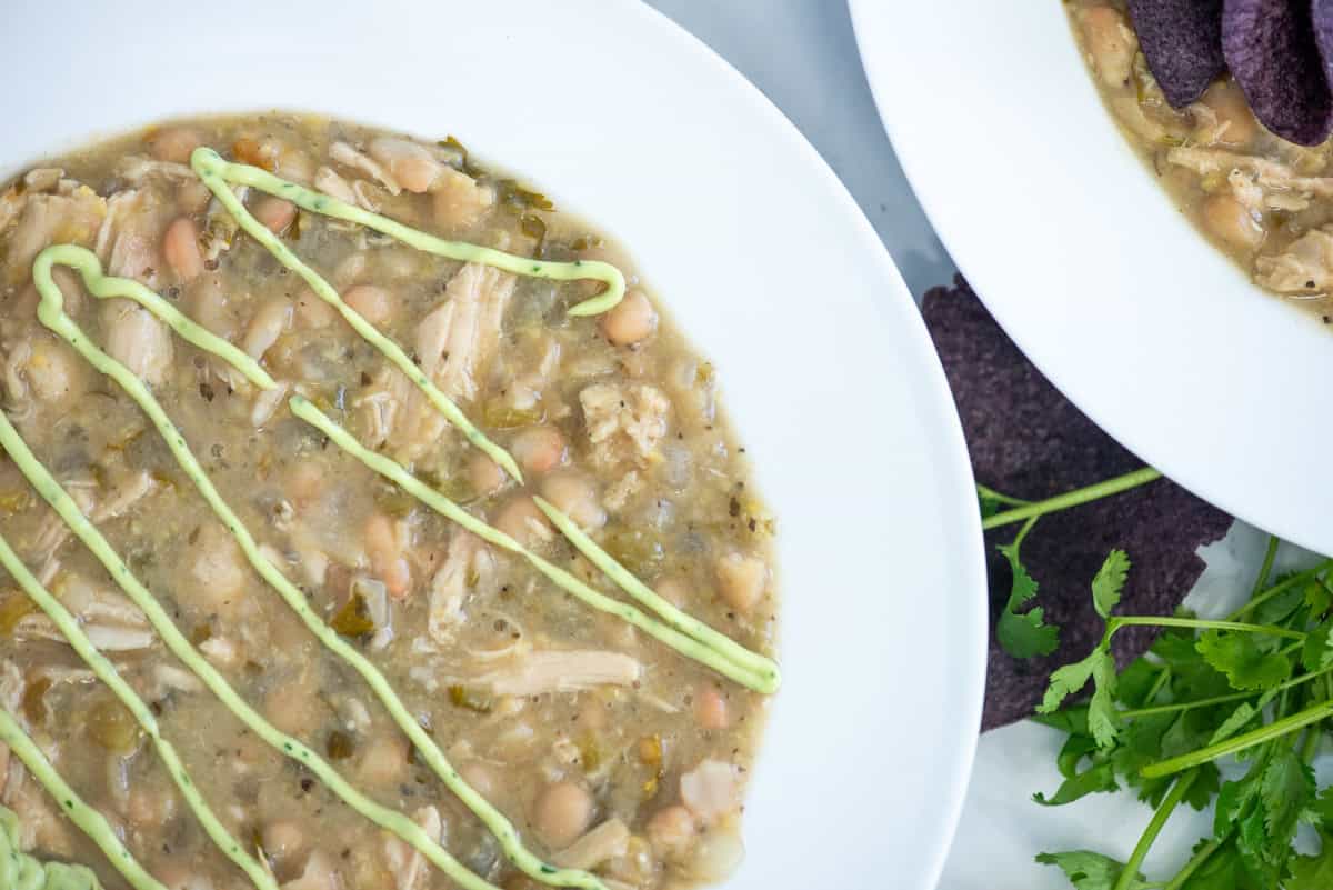 A bowl of turkey and white bean chili garnished with avocado lime crema